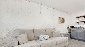Ein Wohnzimmer mit einem hellen Sofa, einem Kissen und einem Gemälde an der Wand.