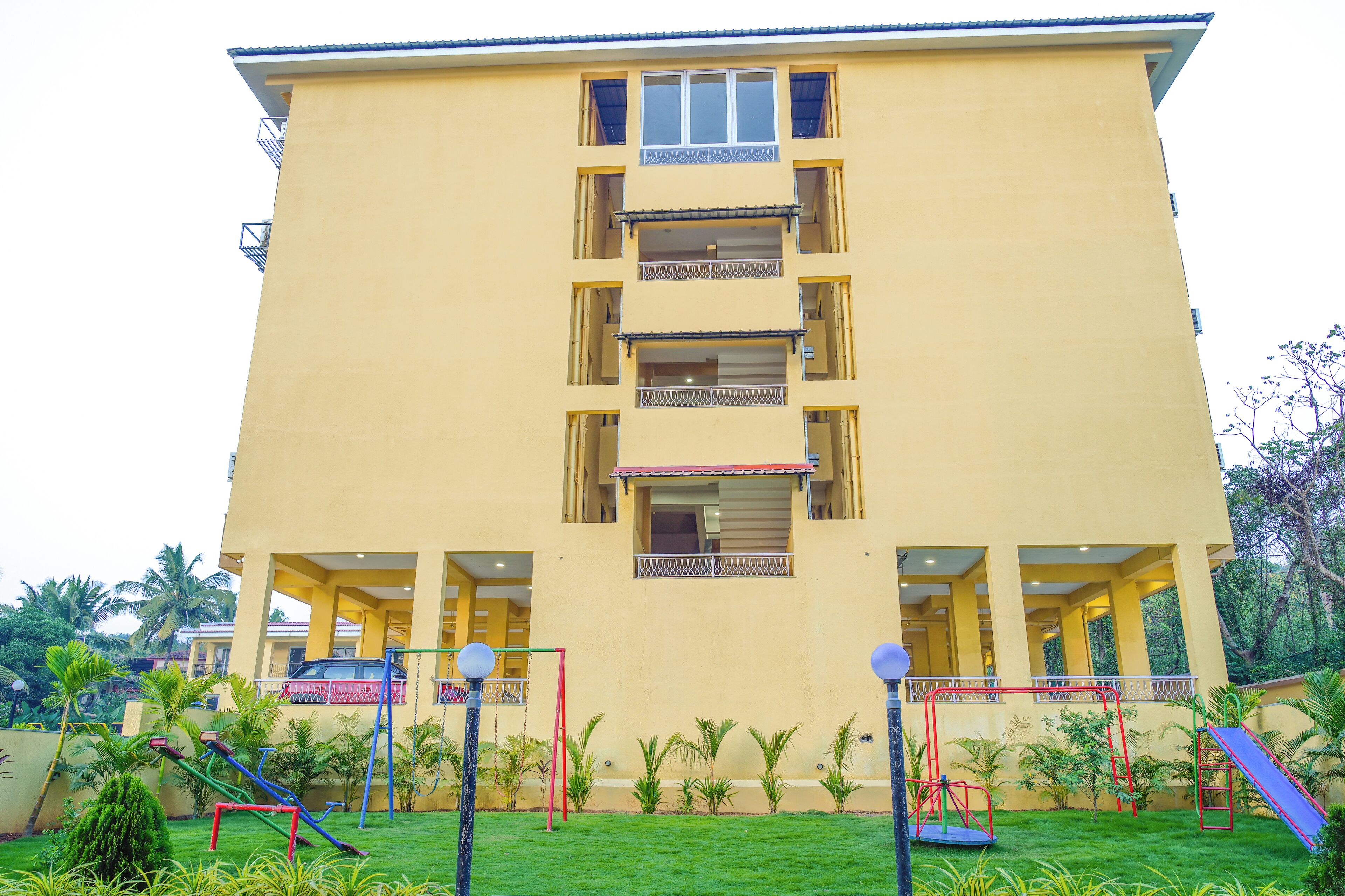 A multi-story building with balconies and a playground area in front.