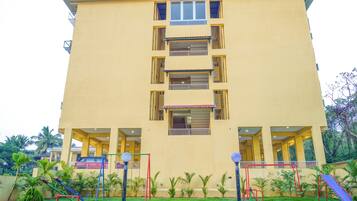 A multi-story building with balconies and a playground area in front.