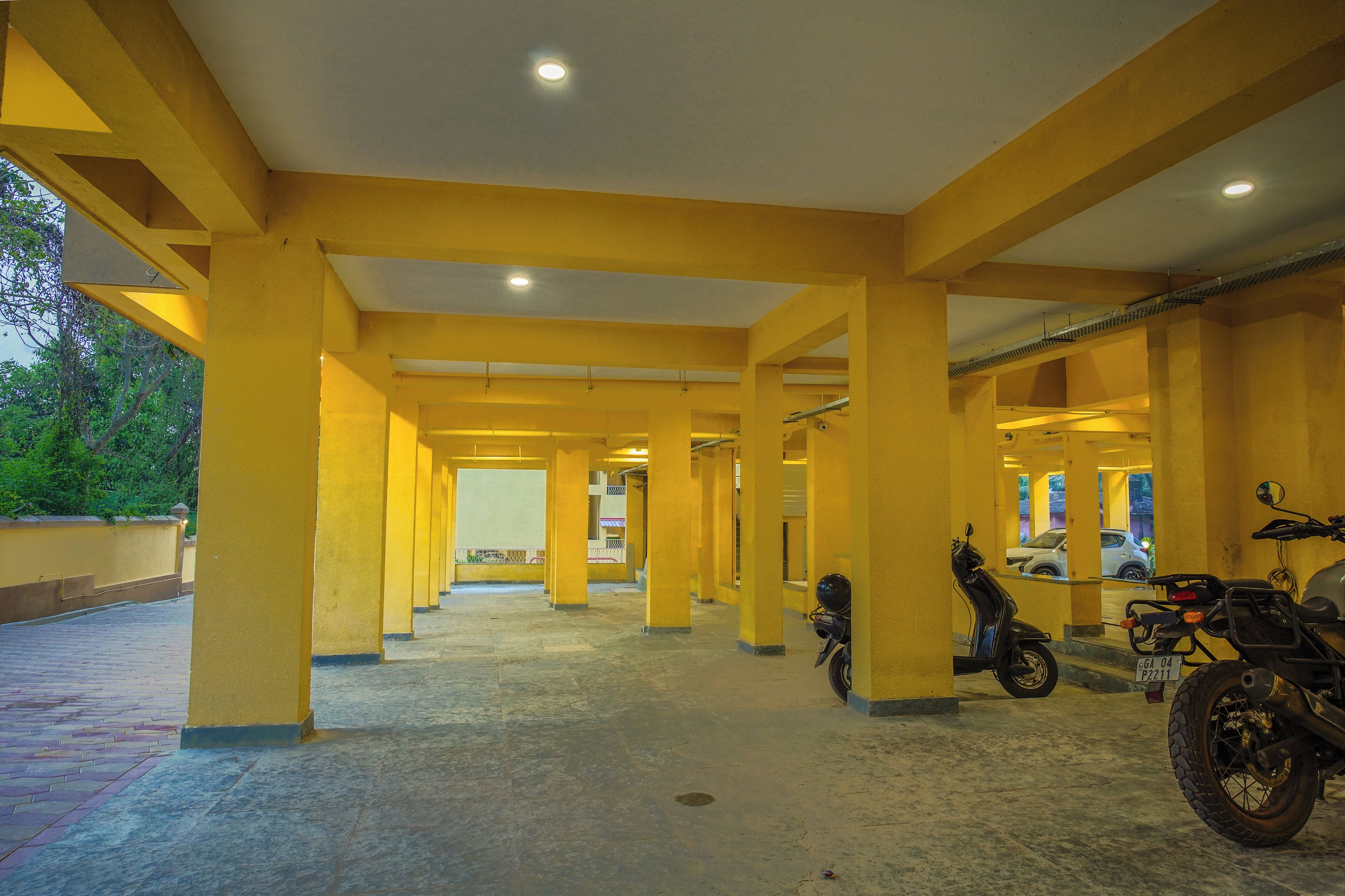 A covered parking area with yellow pillars and a tiled floor.
