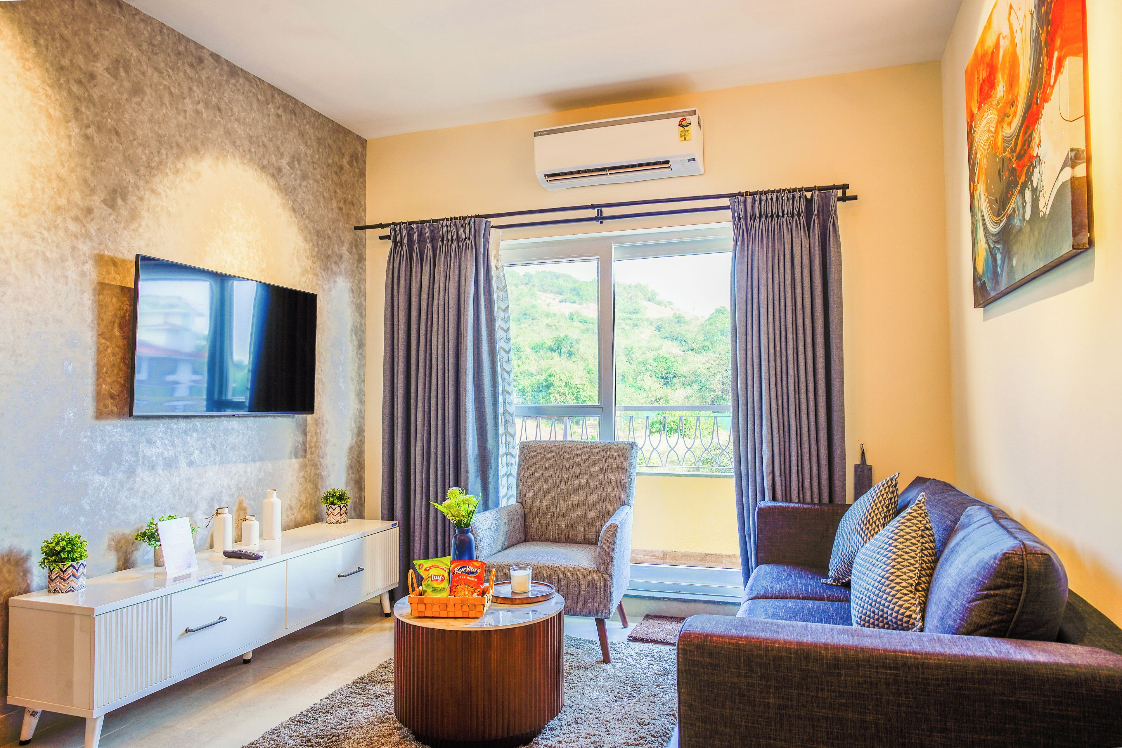 Una sala de estar moderna con un sofá, un sillón y un televisor montado en la pared.