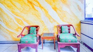 Une pièce comprenant deux chaises en bois et une petite table placée contre un mur dont le motif rappelle le marbre.