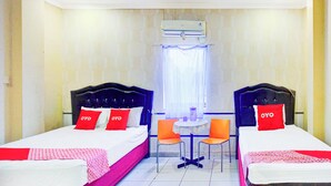Une chambre d’hôtel avec deux lits, une petite table avec des chaises et un appareil de climatisation.