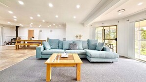 A spacious living room with a sectional sofa, a wooden coffee table, and a large window providing natural light.