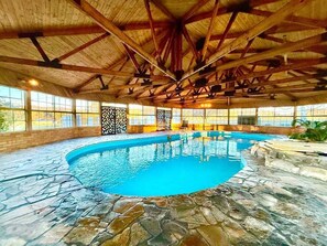 An indoor swimming pool with stone flooring, wooden beams, and large windows. - Marrangaroo Meadows | Rural Manor, 5 Bedroom, 3 Bathroom, A/C, Pets, Indoor Pool (Marrangaroo)