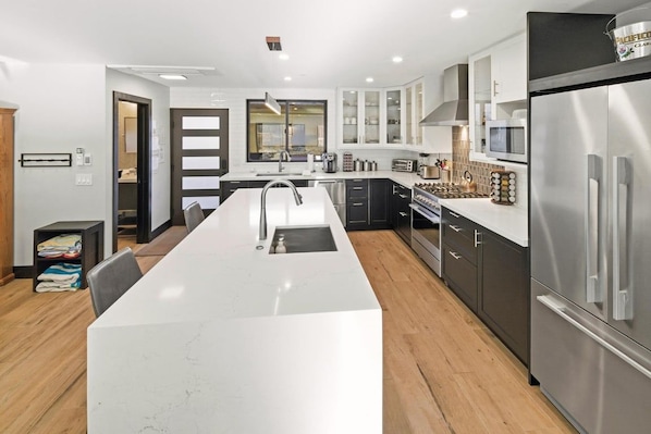 Una cocina moderna con una isla central, electrodomésticos de acero inoxidable y vistas al área de estar contigua.