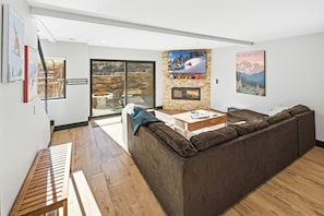 Una sala de estar moderna con un sofá modular, una chimenea y un ventanal grande.