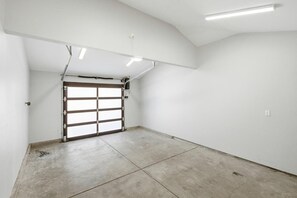 A garage with a concrete floor, a garage door, and fluorescent ceiling lights.