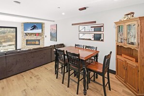 Un comedor con mesa y sillas de madera, un banco empotrado y un mueble de madera con puertas de cristal.