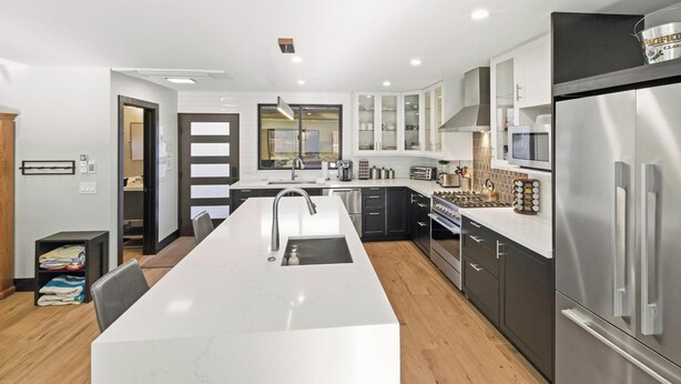 Una cocina moderna con una isla central, electrodomésticos de acero inoxidable y vistas al área de comedor contigua.