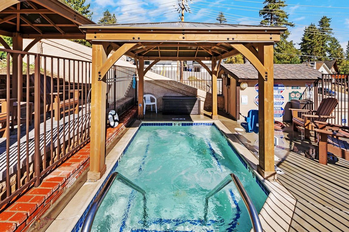 En swimmingpool med træterrasse og overdækket siddeområde.