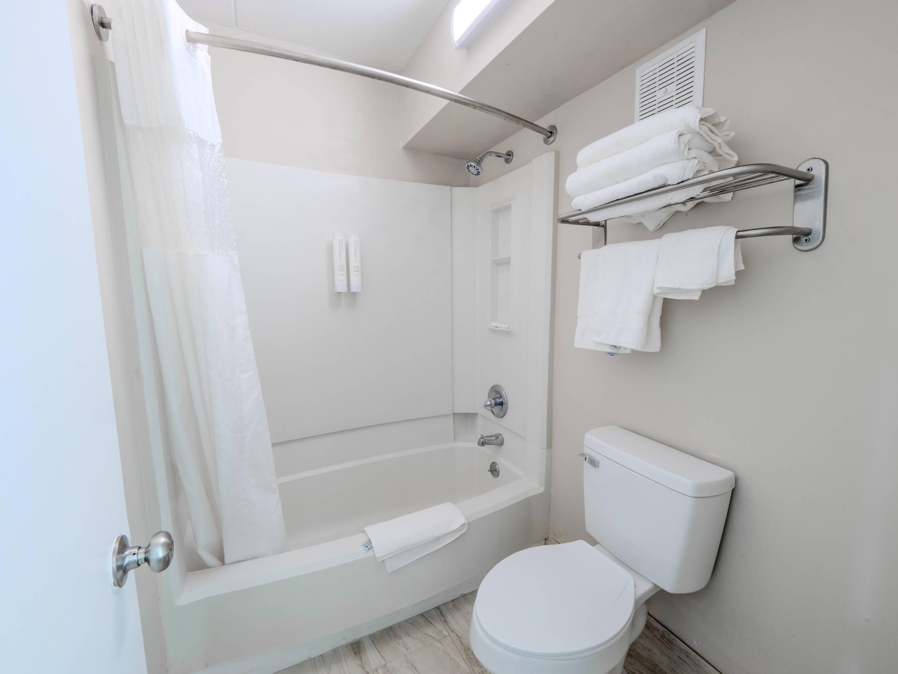A modern bathroom with a bathtub, toilet, and towel rack.