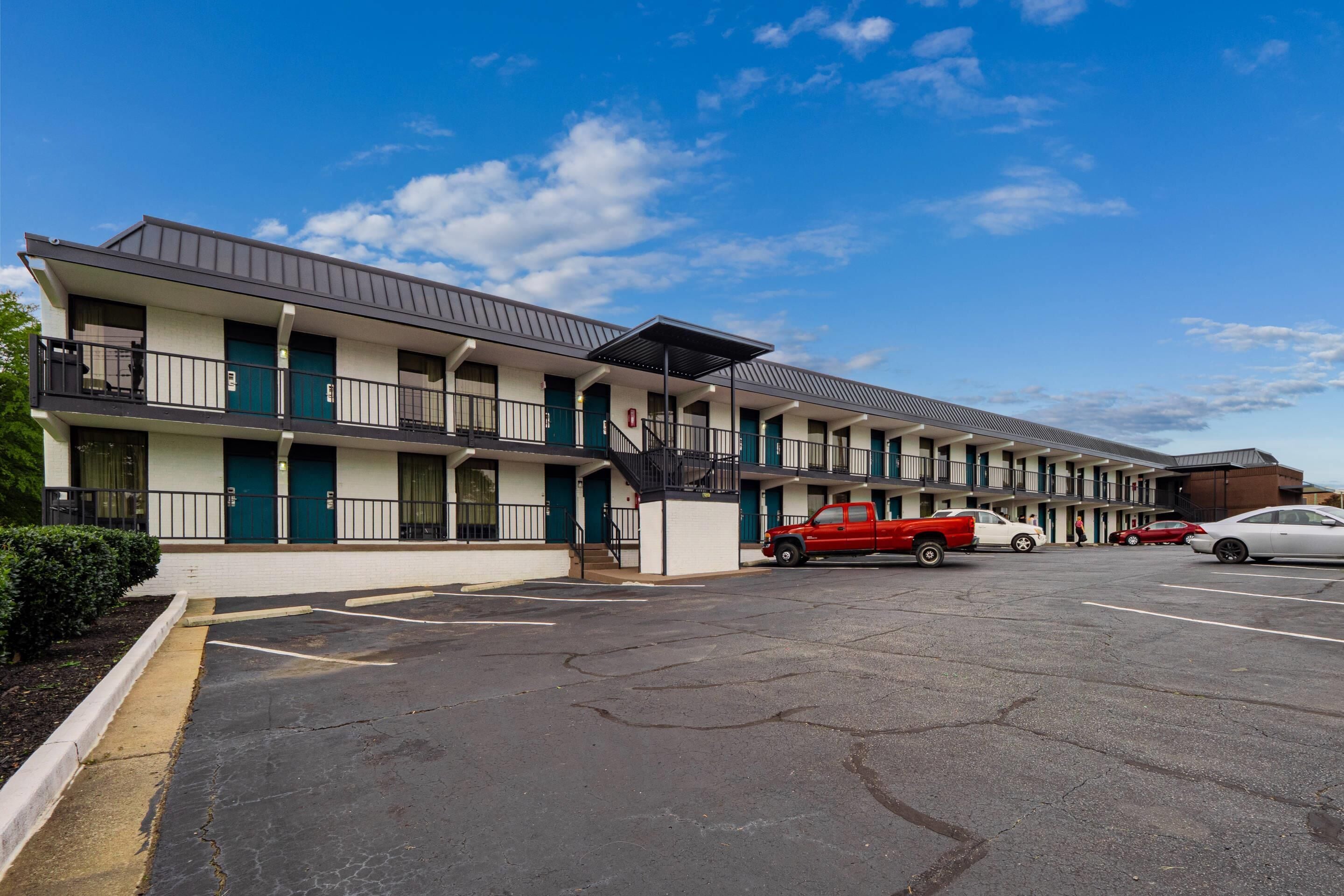 A motel with multiple floors, a parking lot, and a clear blue sky.
