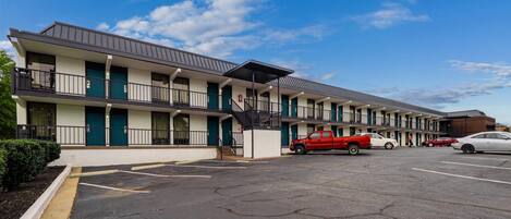 A motel with multiple floors, a parking lot, and a clear blue sky.