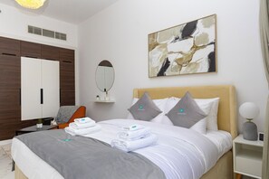 Une chambre d’hôtel avec un lit, un bureau, une chaise, un miroir et un tableau accroché au mur.