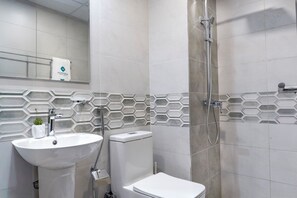 Une salle de bain moderne avec un lavabo, des toilettes et une douche, le tout de couleur blanche.
