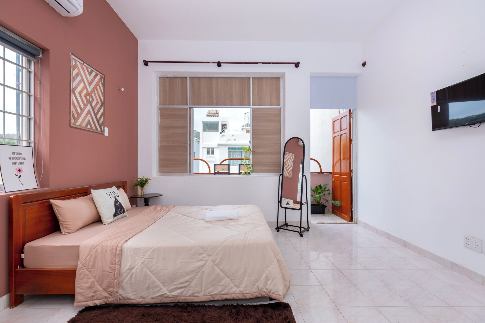 Ein Schlafzimmer mit Bett, Fenster, Fernseher und Tür.