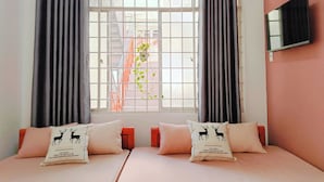 A hotel room with two beds, a window with a view of a building outside, and a flat-screen TV mounted on the wall. - Anh's House Modern Homestay 2 (Ho Chi Minh City)
