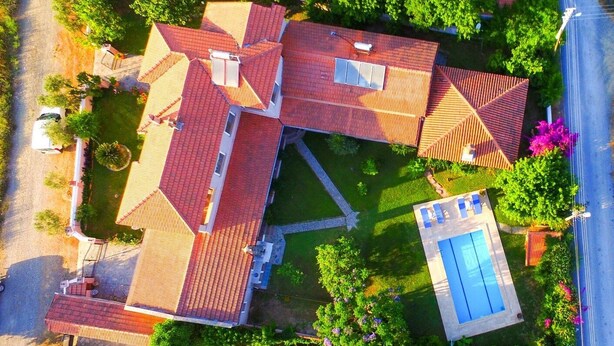Vista aérea de una propiedad residencial con varias edificaciones, piscina y abundante vegetación.