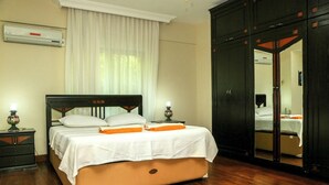 Un dormitorio con cama, mesitas de noche, aire acondicionado, armario y espejo.