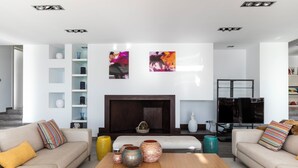A modern living room with a fireplace, sofas, a coffee table, and decorative items.