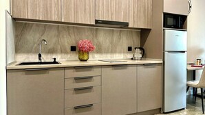 A modern kitchen with a marble backsplash, a stainless steel sink, a vase with pink flowers, and a built-in microwave.