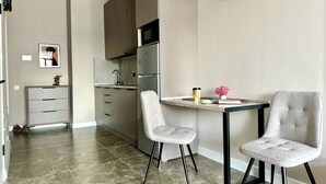 A modern kitchen with a built-in microwave, a small sink, and a dining area with two chairs and a table.
