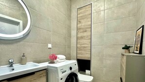 A compact bathroom with a washing machine, a sink, and a toilet.