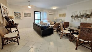 A spacious living room with a sofa, dining table, and wicker chairs.