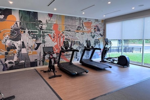 A gym with treadmills, stationary bikes, and a large mural on the wall. - Hawthorn Extended Stay by Wyndham Mebane (Mebane)