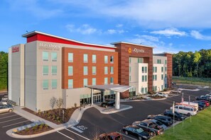 A hotel with a modern design, featuring a covered entrance and a parking lot with multiple vehicles. - Hawthorn Extended Stay by Wyndham Mebane (Mebane)