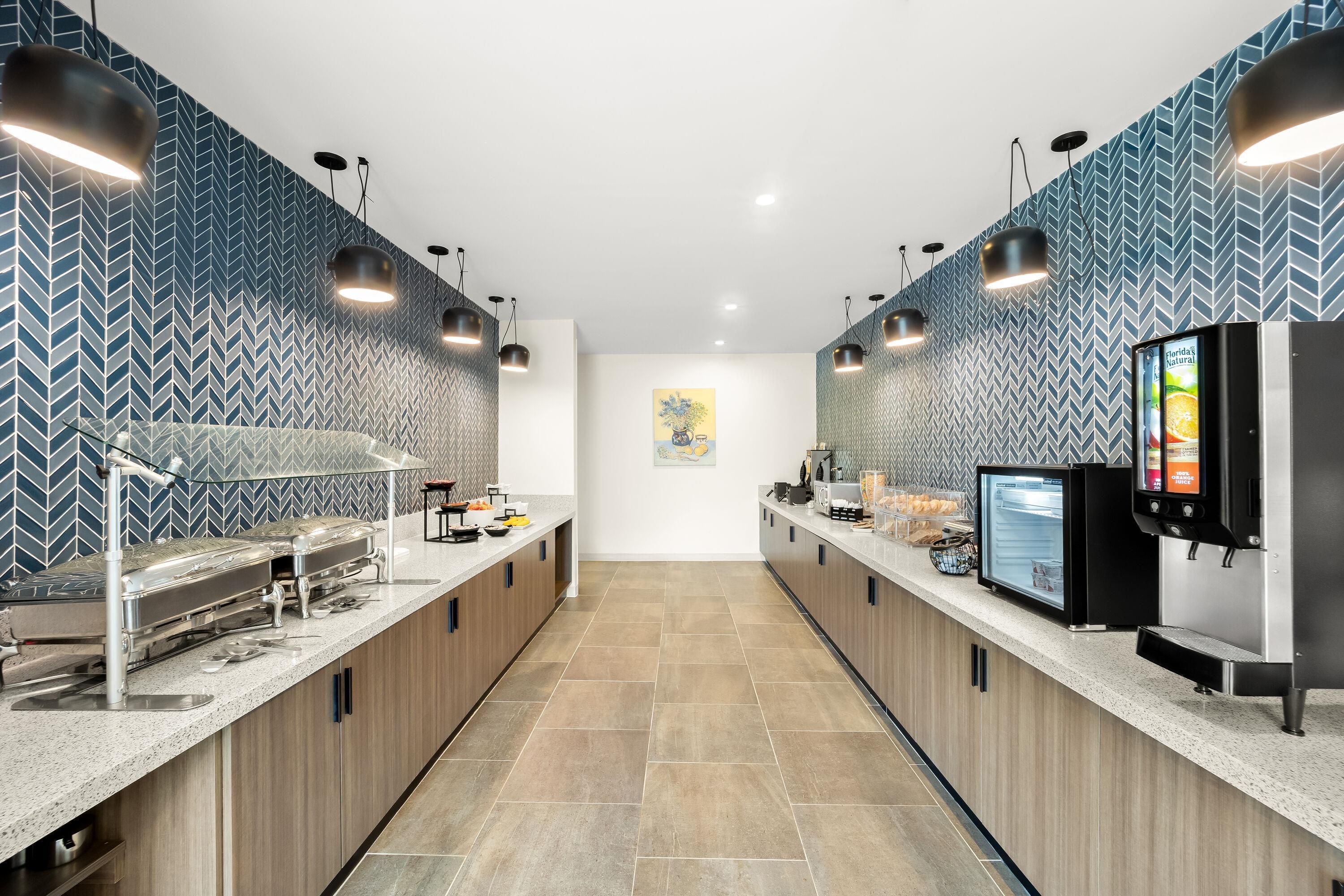 Una cocina moderna con una encimera larga, electrodomésticos de acero inoxidable y una pantalla digital de menú.