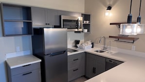 Una cocina moderna con un refrigerador de acero inoxidable, microondas y lavavajillas.