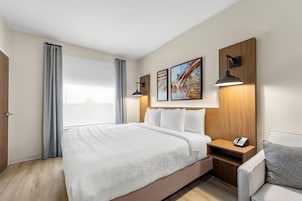 Una habitación de hotel con una cama grande, una mesita de noche con un teléfono y dos lámparas de pared.