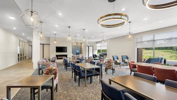 Un espace de repas moderne agrémenté de luminaires suspendus hexagonaux, d’une cheminée et offrant une vue sur l’extérieur.