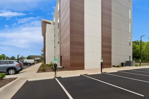 A parking lot with electric vehicle charging stations and a building with a modern design. - Hawthorn Extended Stay by Wyndham Mebane (Mebane)