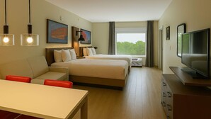 Una habitación de hotel con cama, televisor, escritorio y ventana con cortinas.