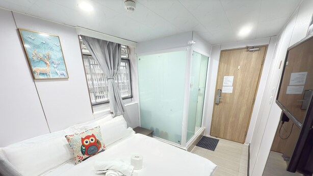 A hotel room with a bed, a window with curtains, a door, and a wall-mounted picture. - Fortune Inn (Kowloon)