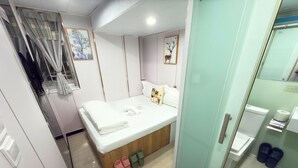 A bedroom with a bed, a bedside table, a mirror, and a shower area. - Fortune Inn (Kowloon)
