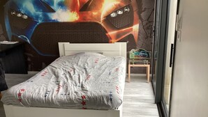 Et soveværelse med seng, et vægmaleri af en bil og et lille bord med en legetøj.