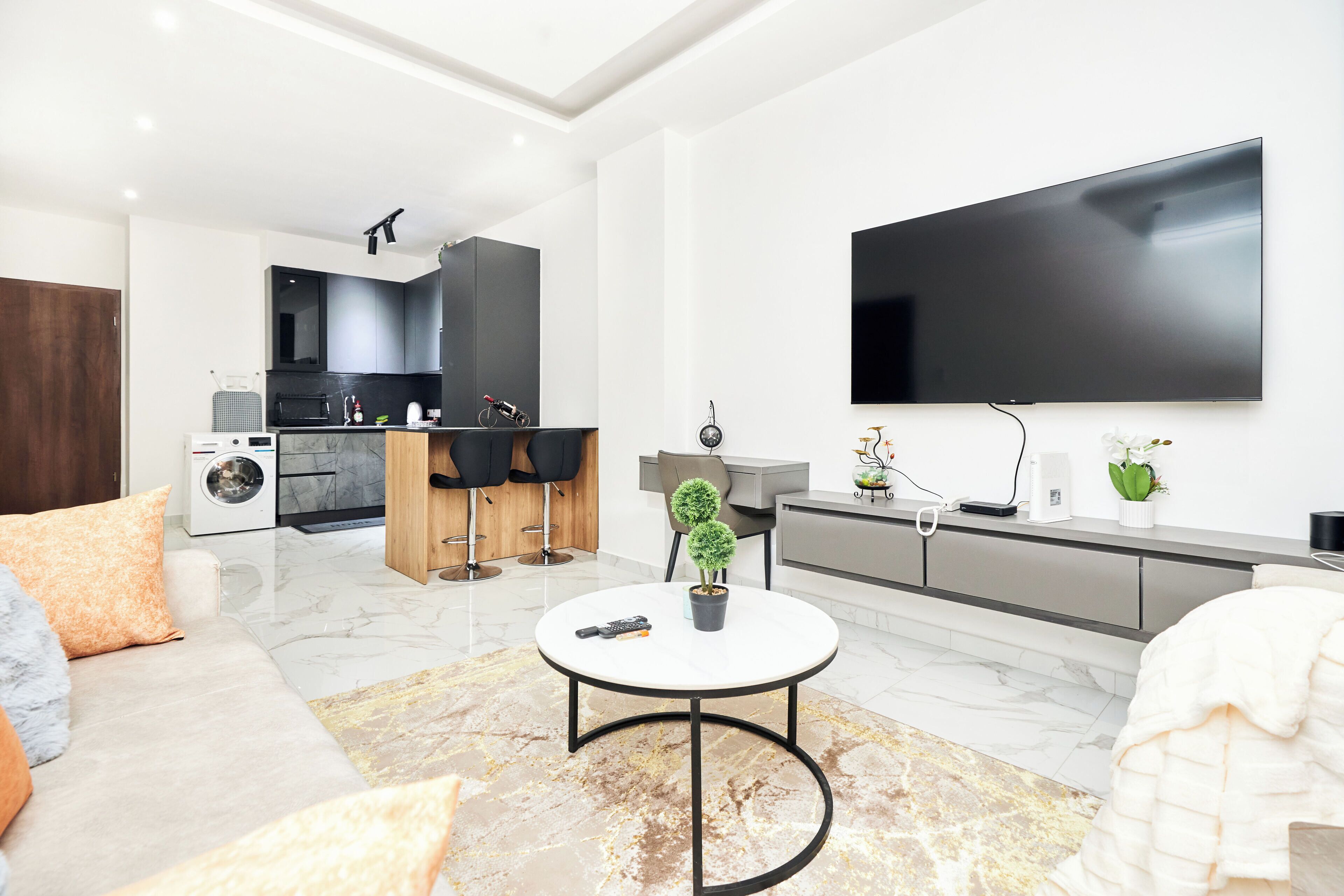 A modern living room with a sofa, a coffee table, and a TV mounted on the wall.