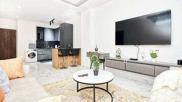A modern living room with a sofa, a coffee table, and a TV mounted on the wall.