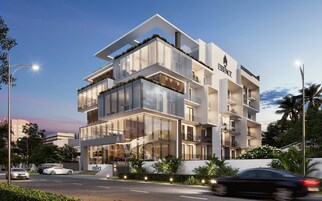 A modern multi-story building with a prominent 'ESSENCE' sign, large glass windows, and balconies with plants.