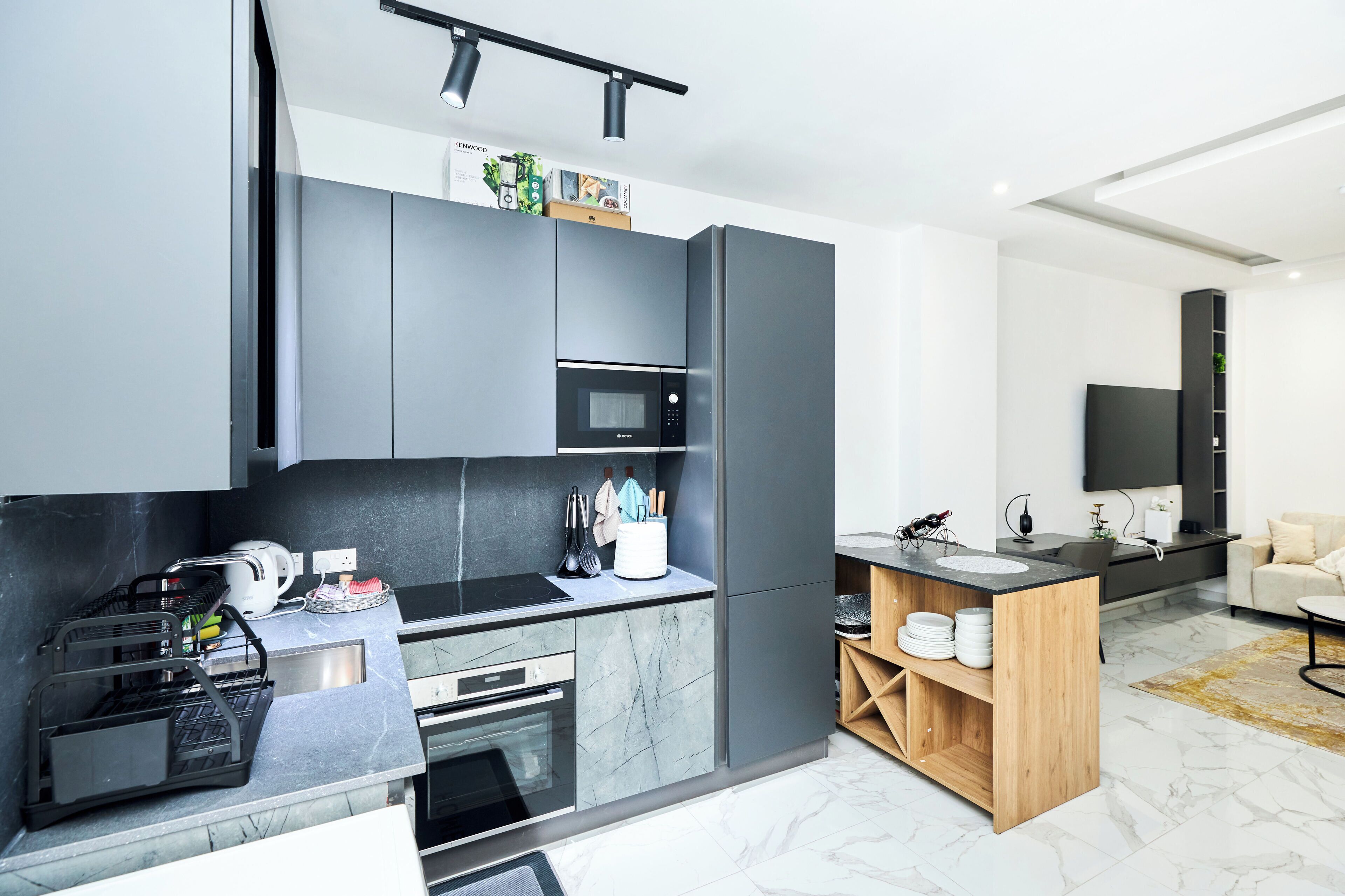 A modern kitchen with a built-in oven, microwave, and a sleek black countertop.