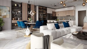 A modern living room with a white sofa, blue chairs, and a dining area with a round table. - Quao Realty - The Essence (Accra)