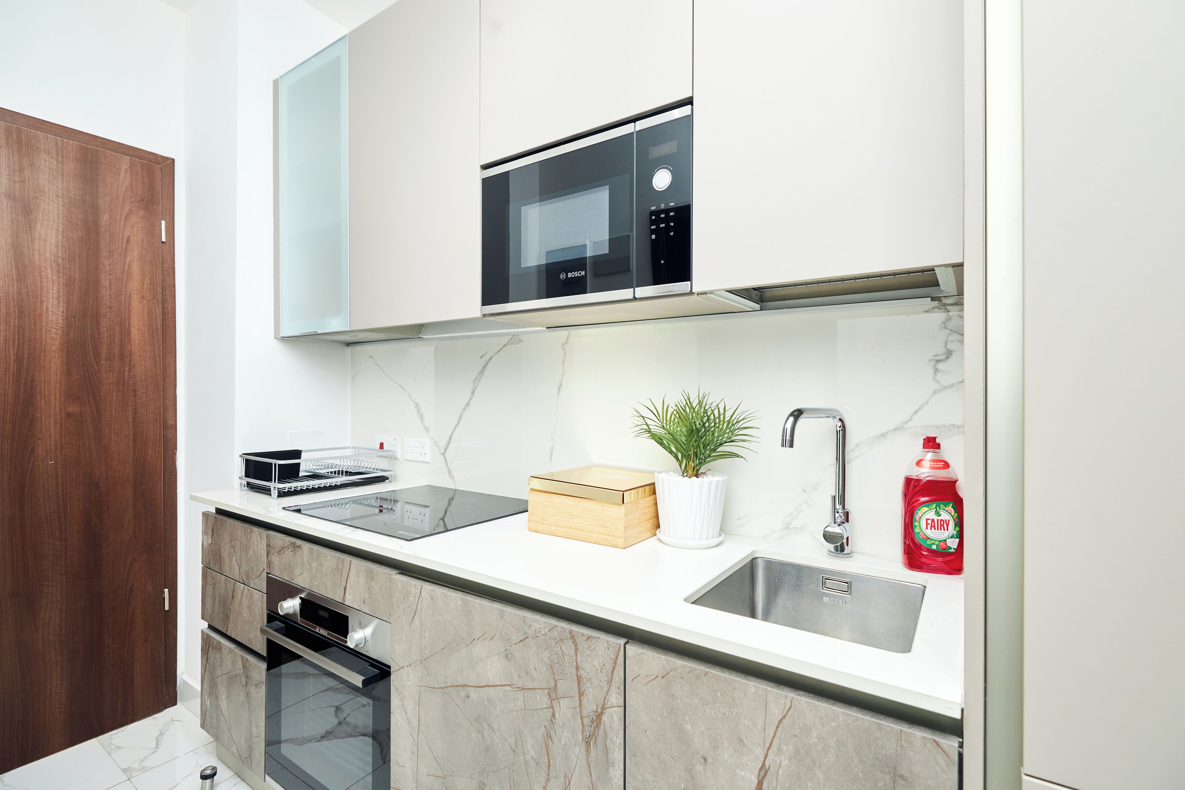 A modern kitchen with a built-in microwave, a sink, and a wooden box on the counter.