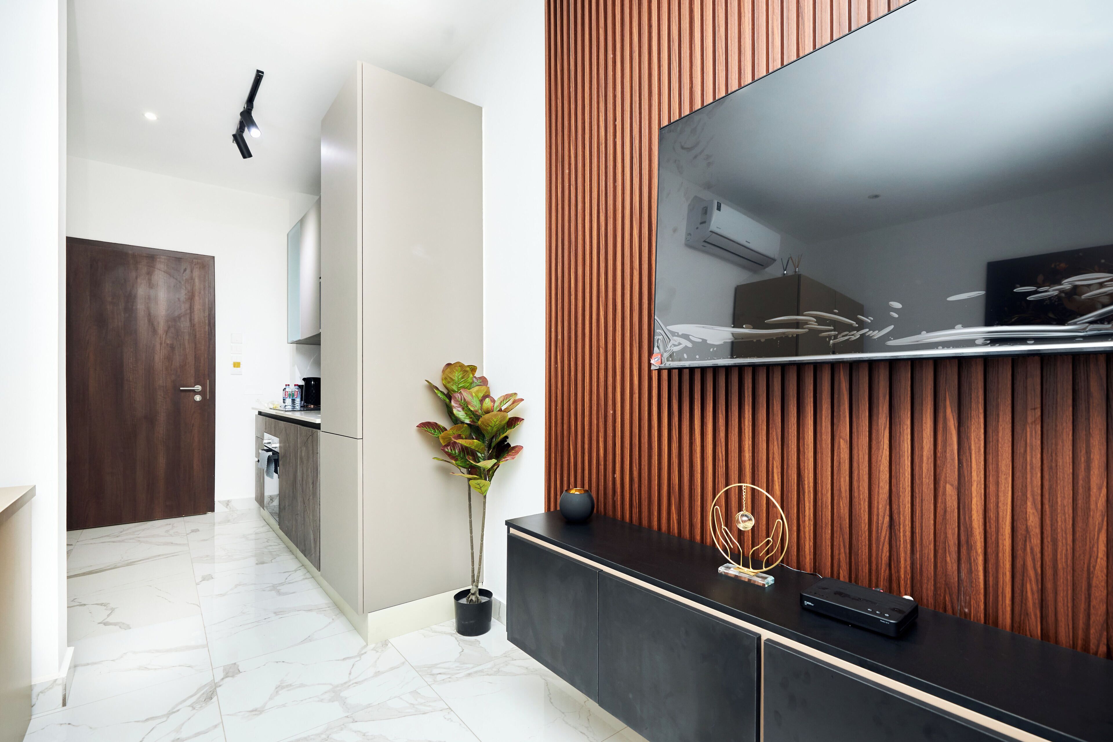 Una cocina moderna con un mueble de madera, una planta en maceta y un televisor de pantalla plana montado en una pared de madera.