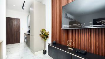 Una cocina moderna con un mueble de madera, una planta en maceta y un televisor de pantalla plana montado en una pared de madera.
