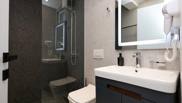 A modern bathroom with a glass-enclosed shower, a toilet, a sink with a mirror, and a hairdryer on the countertop.