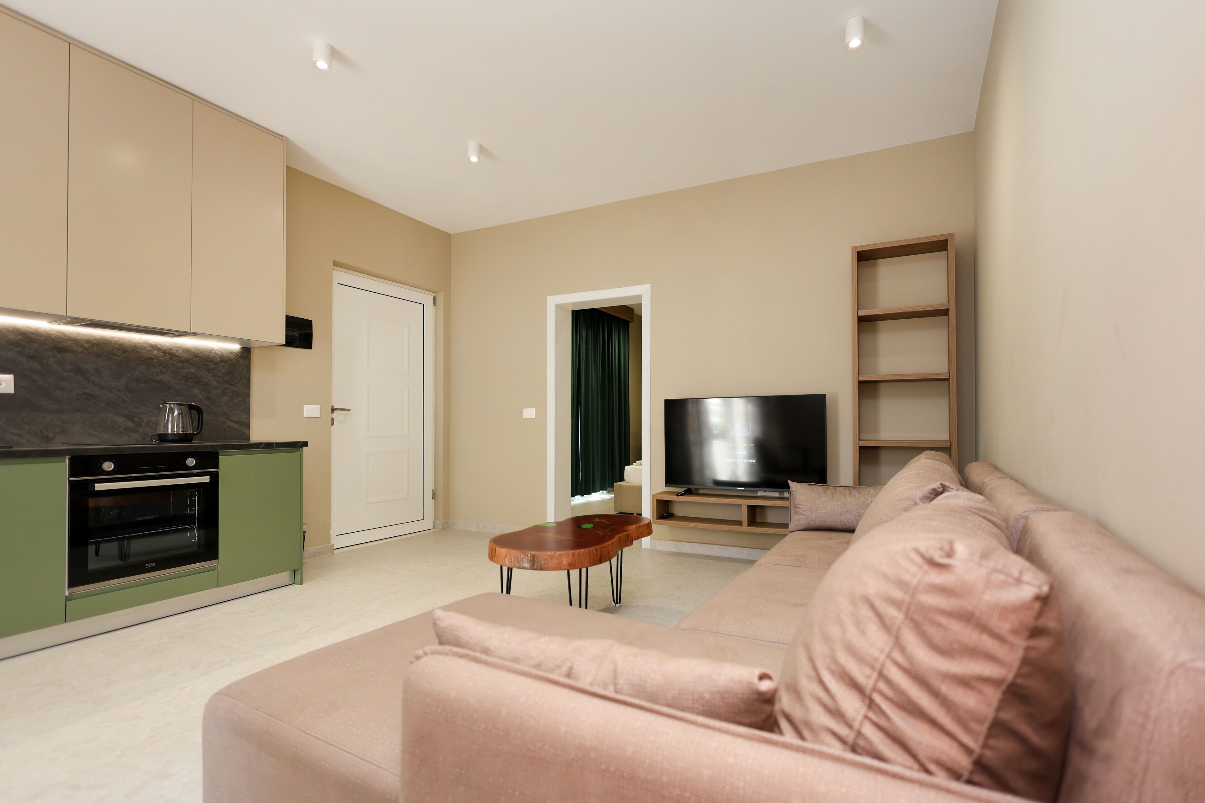 Una sala de estar moderna con sofá, televisión y área de cocina.